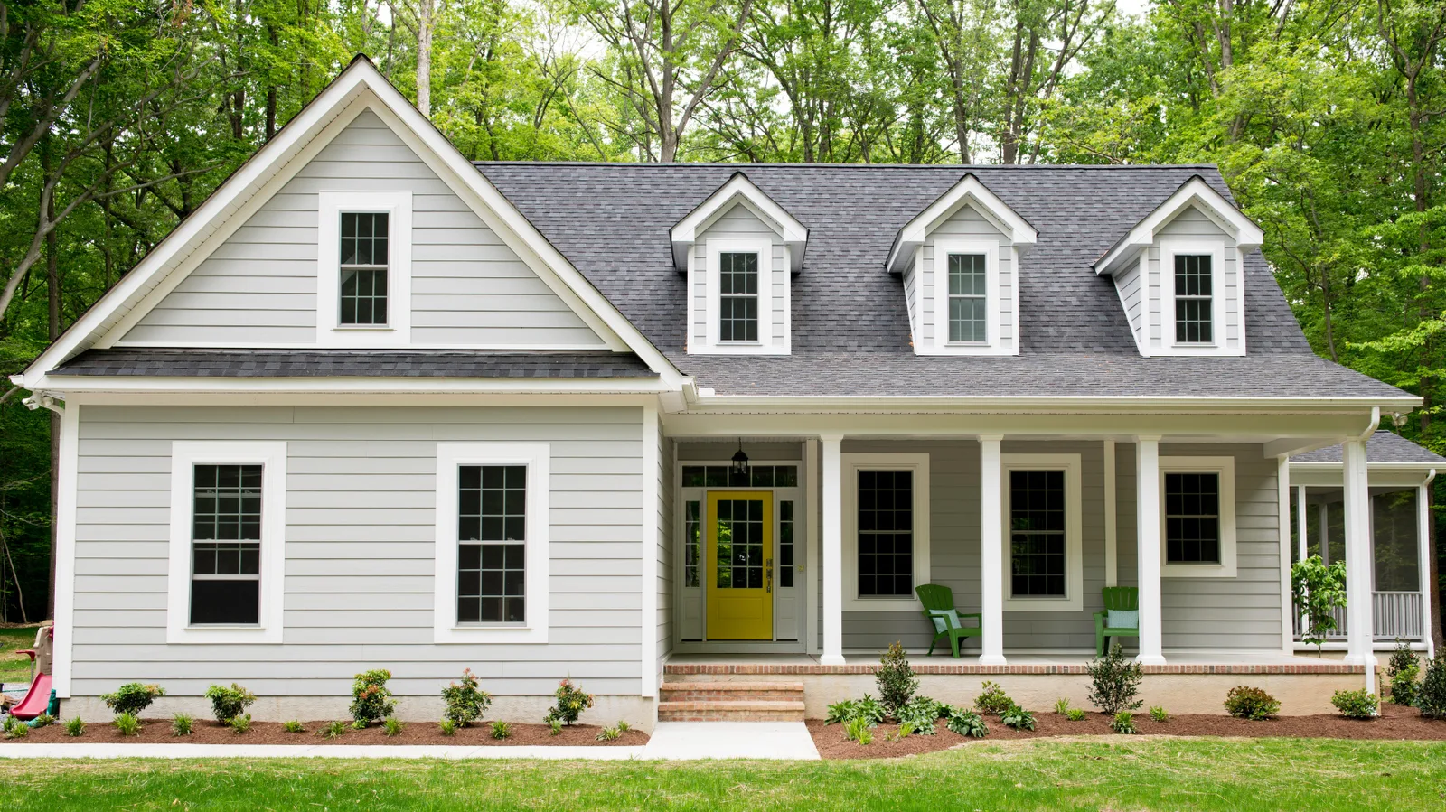 House exterior with a broad shingle roof, dormers and a covered porch